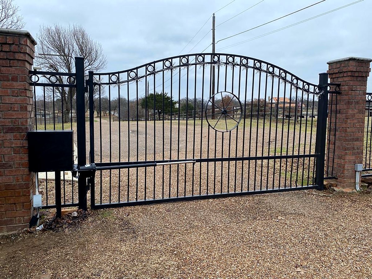 Arched wrought iron automatic gate between brick columns installed by Garage Tec
