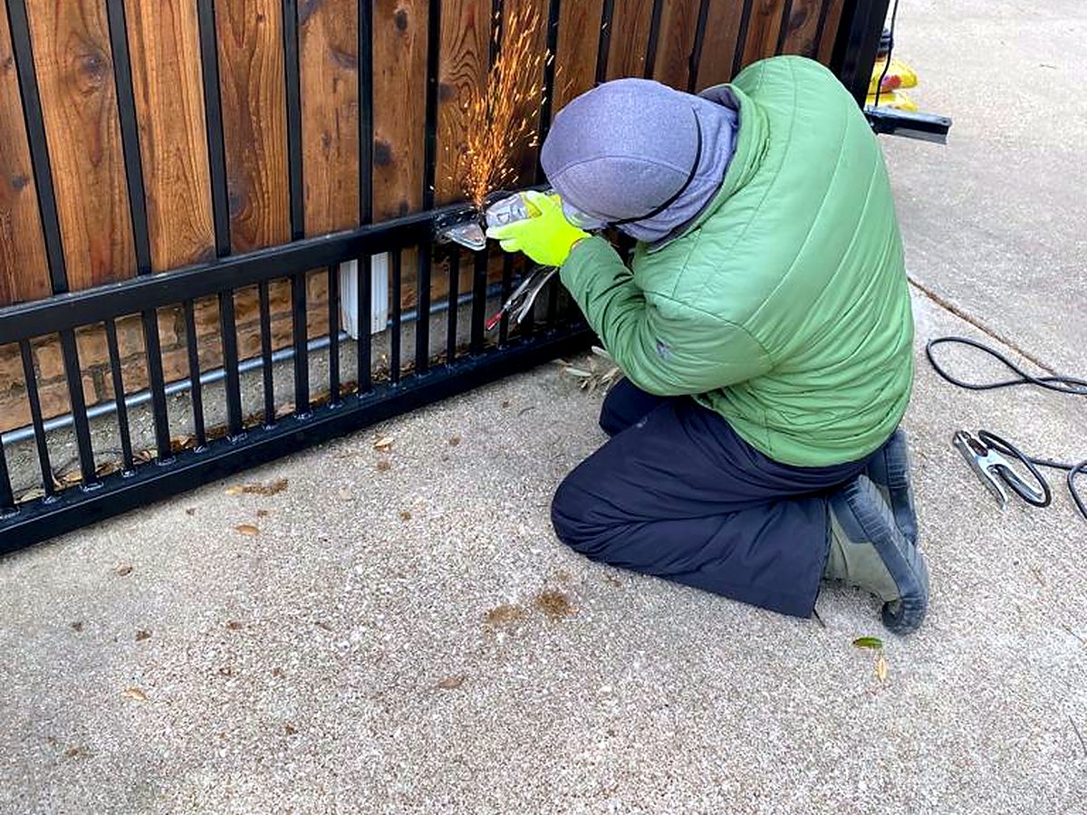 Garage Tec technician welding a repair on a steel and wood gate