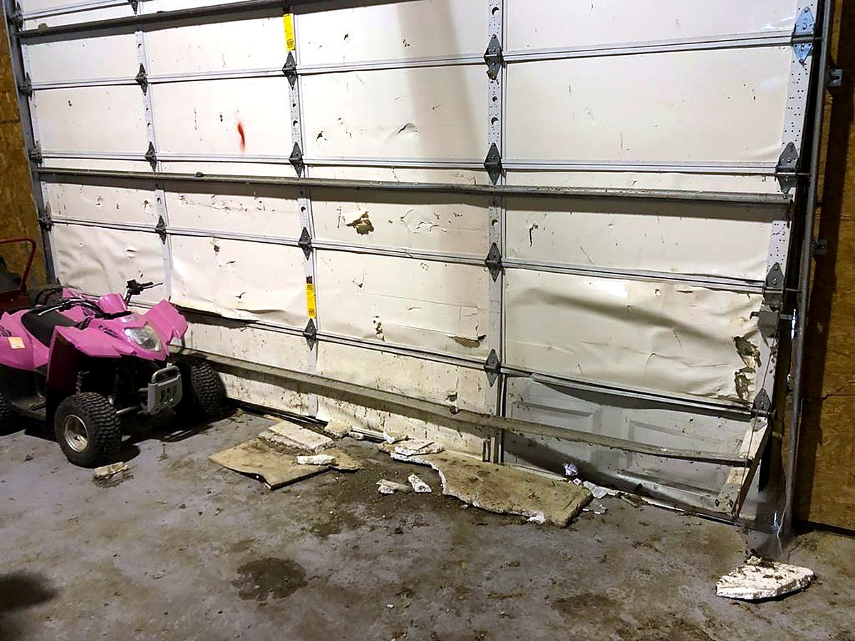 Garage door with crushed panels before panel replacement Garage door with crushed panels before panel replacement
