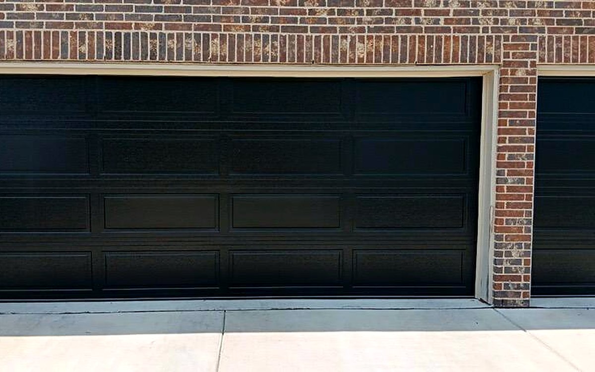 New black steel residential garage doors on a brick home New black steel residential garage doors on a brick home